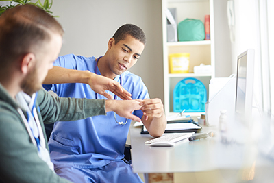 gp examines male patients hand. He is checking the flexibility in the wrist and fingers.