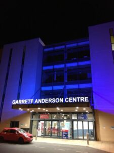 Image of the front of Ipswich Hospital light up with blue lights.