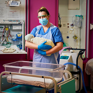 Bethany, a midwife, holding a baby at a birthing unit in Newcastle