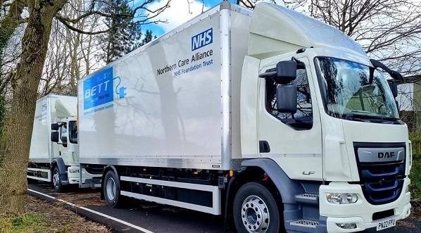 Photo of a white electric heavy goods vehicle (Lorry) with the NHS logo on the side.