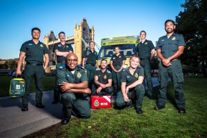 Image shows London Ambulance Service paramedics posed in front of Tower Bridge on a sunny day in London.