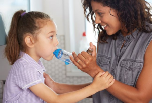 Girl using an inhaler with her mother.