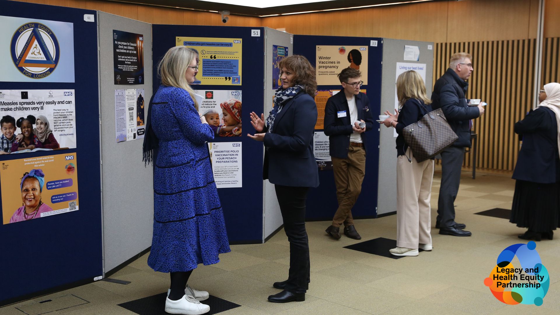 Health care workers and community leaders gathered in front of a display board at the LHEP event in March 2024