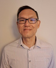 App Ambassador Emmanual Chan looks at the camera. He is wearing a light coloured shirt and wears black glasses.