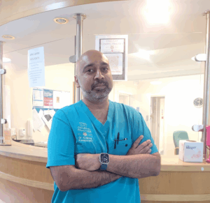 Dr Krishna Kasaraneni stands in front of his GP reception desk