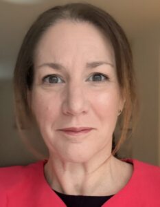 Dr Hannah Brown looks at the camera. She has dark brown hair and is wearing a red top.