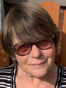 Head and shoulders picture of lady in her sixties wearing sunglasses