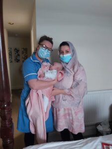 Midwife, mum and baby stood together in room