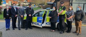 Group of people stood by the side of police car