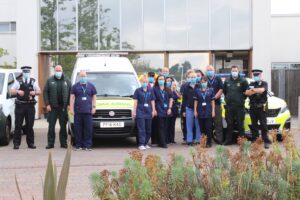 Group of people stood next to an ambulance and police car