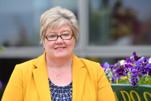 Woman wearing glasses and yellow jacket looking at camera