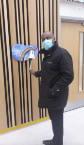 Image of a man in a mask, ringing a bell to mark the end of his cancer treatment