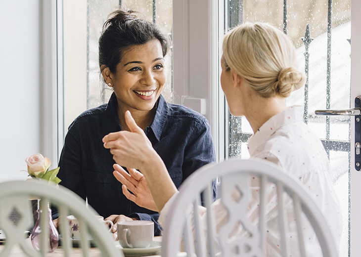 Women are sitting at a table in a cafe, socialising over tea.