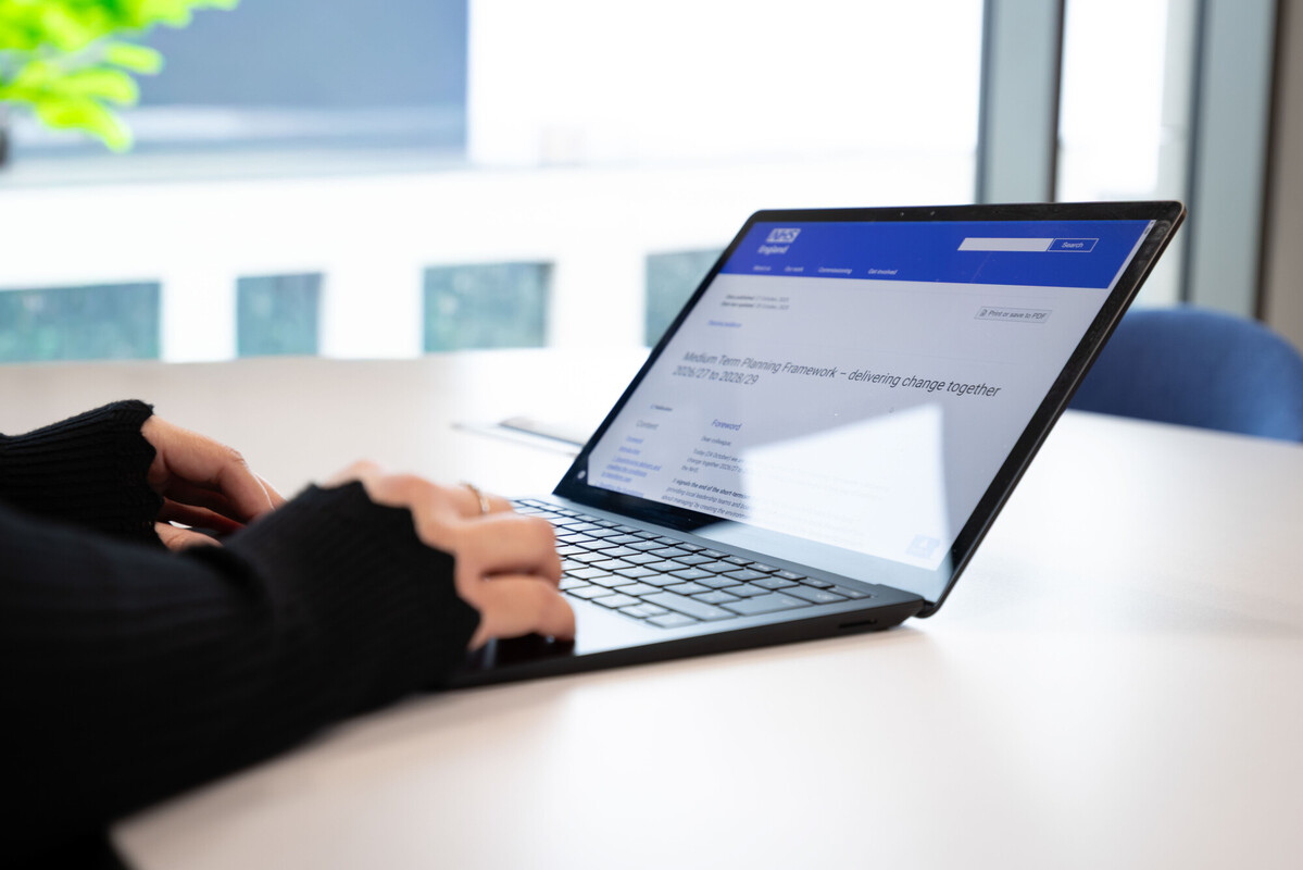 Photo of a persons hands typing on an open laptop