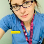 a nurse in scrubs wearing glasses
