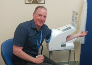Photo shows a man with his hand in a blood pressure machine.