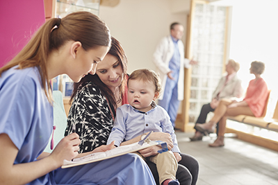 A mother and child chat with a nurse