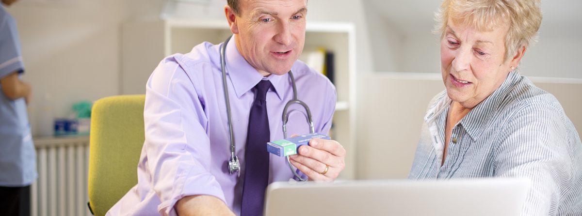 A GP with a patient sitting in front of a computer