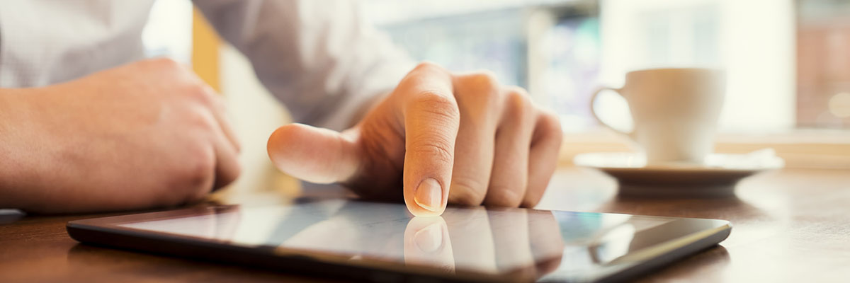 A man uses a tablet in a cafe