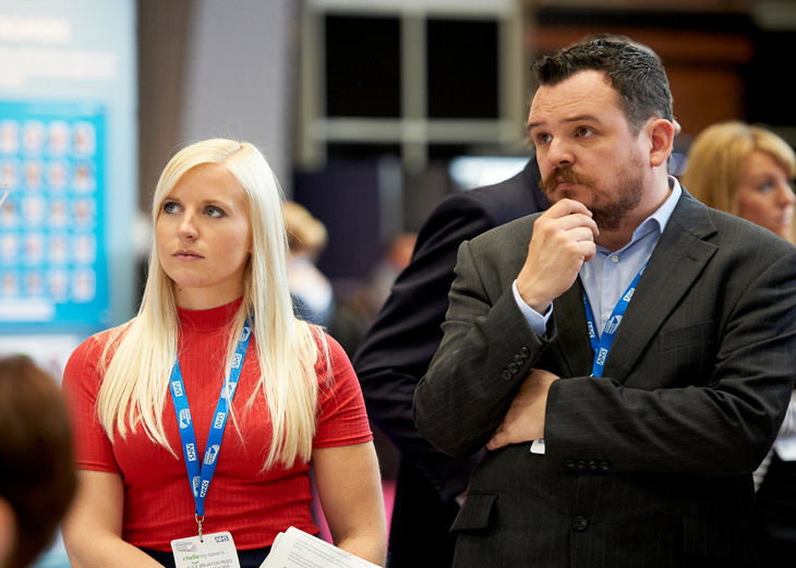 Two people listen to a speaker at Expo