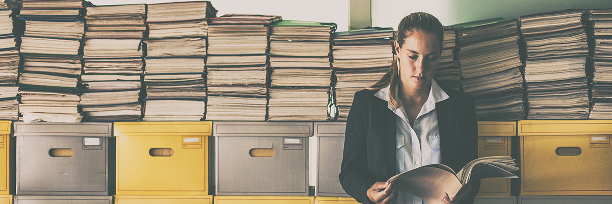A woman surrounded by archive boxes and paper