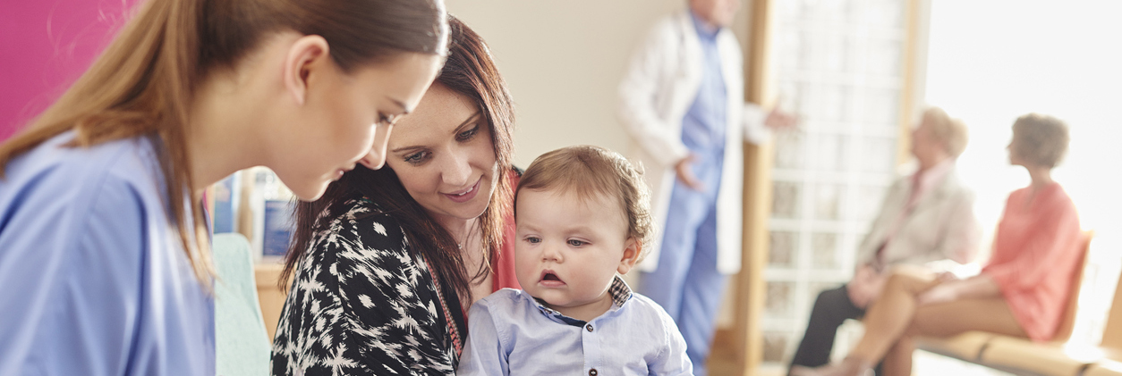 A nurse sits with a mother and toddler