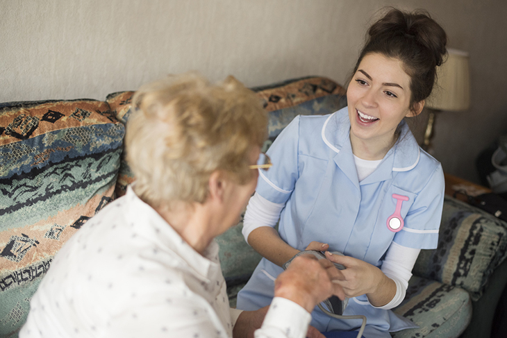 A smiling nurse chats with a patient