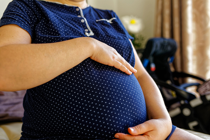 A woman cradles her pregnancy bump