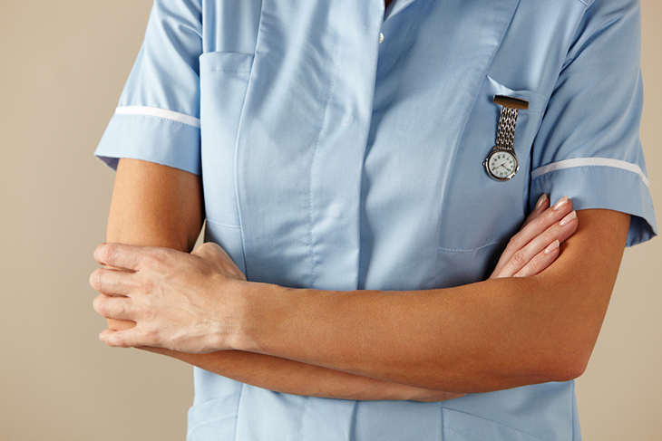 A nurse stands with her arms folded