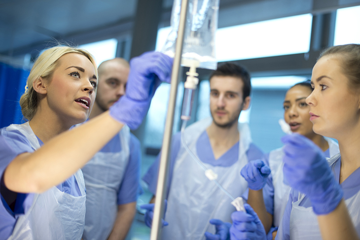 A nurse shows colleagues how to use an IV drip