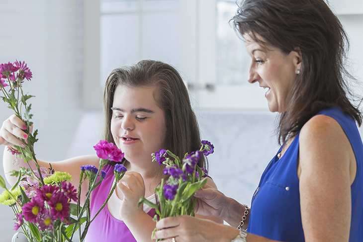 A girl with Down's Syndrome arranges flowers with her mother