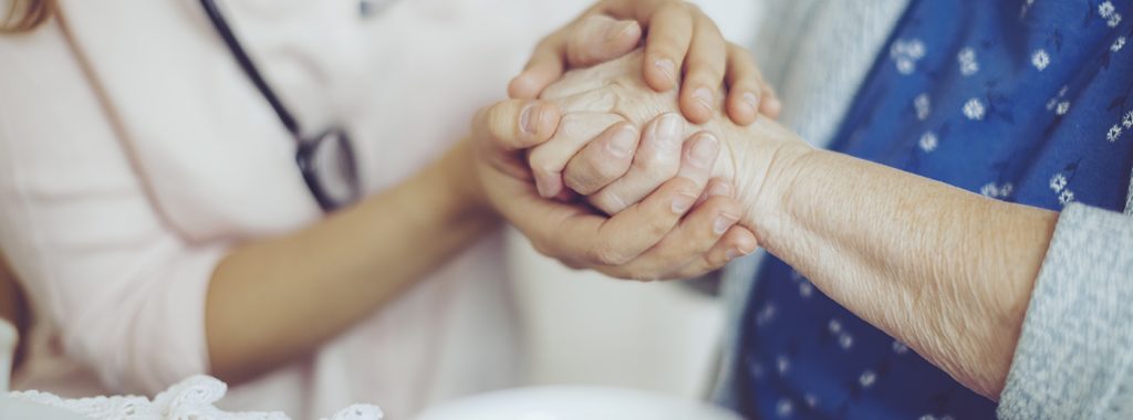 Healthcare professional and patient holding hands