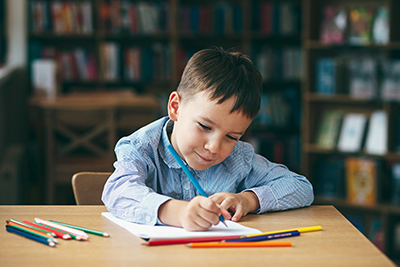 Young boy sat at a desk doing homework.