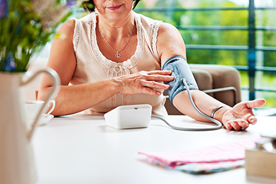 Mature woman sitting at the table at home and checking her blood presure.