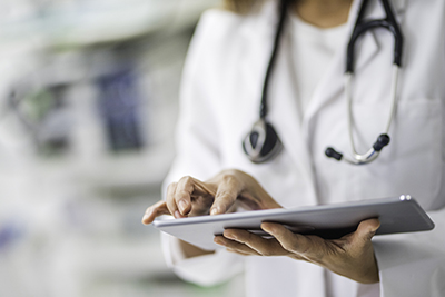 Female doctor using digital tablet in clinic.