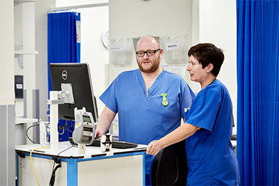 Male and female nurses talking while looking at a computer screen.