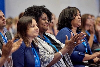 Women in the crowd at Expo 2019 smiling and clapping