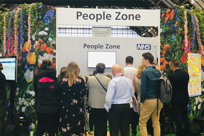 Group of people stood in front of a stand with the title People Zone.