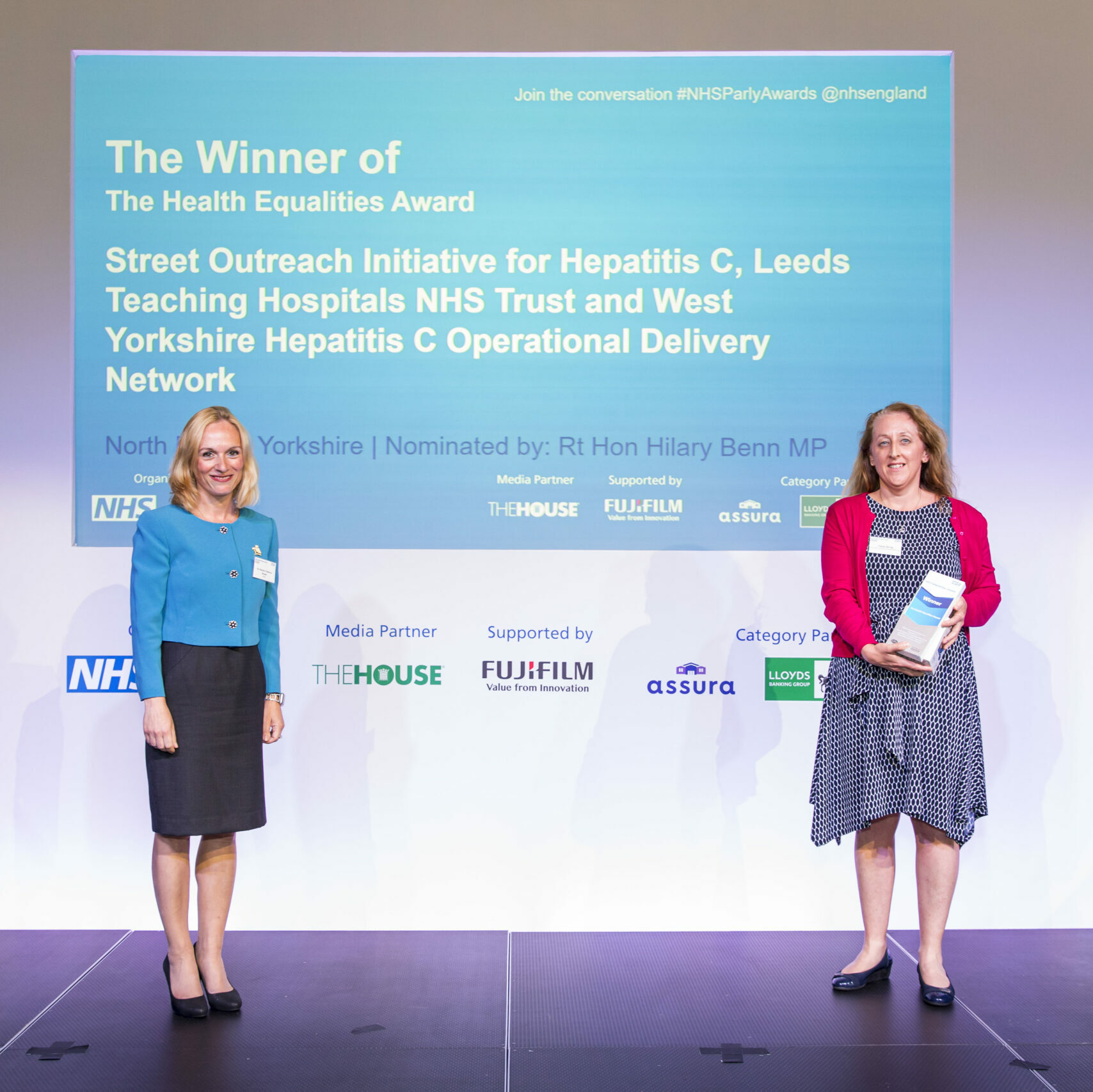 A member of the Street Outreach Initiative for Hepatitus C team is stood on stage receiving The Health Equalities Award