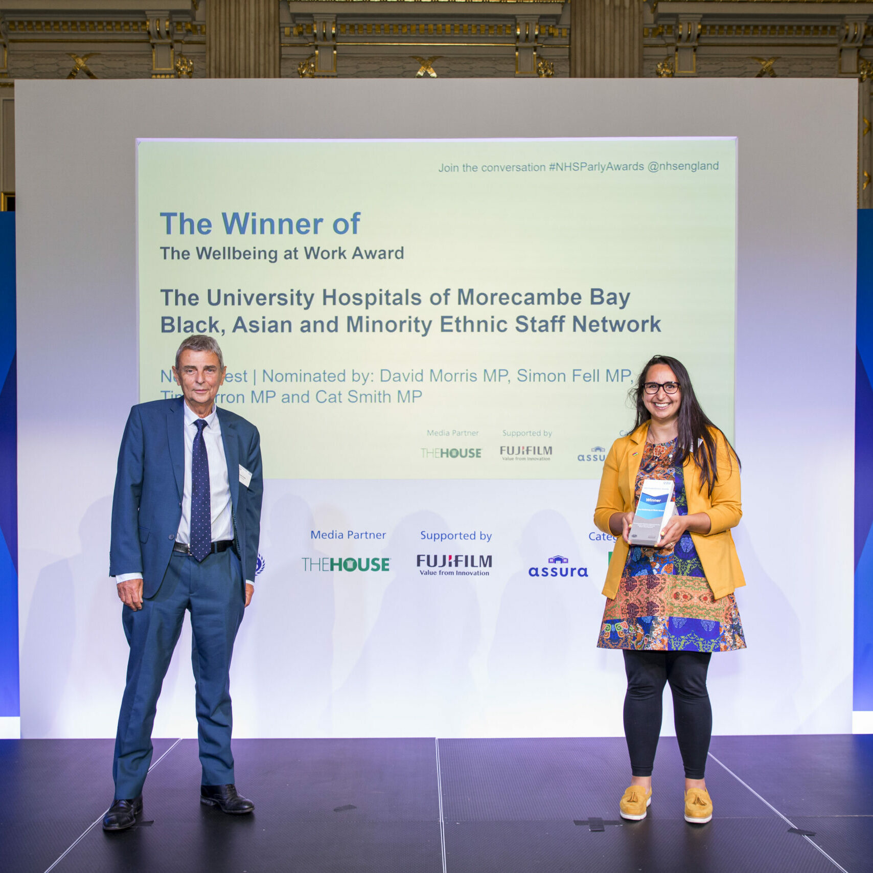 A member of the University Hospitals of Morecambe Bay Black, Asian and Minority Ethnic Staff Network is stood on stage receiving The wellbeing at work award