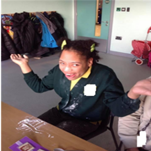 Justina at her school desk, happily painting.