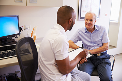 Senior Male Patient Working With Physiotherapist In Hospital