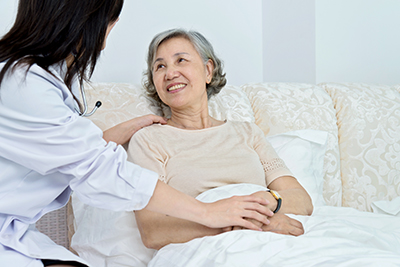 Female doctor talking to senior patient in hospital bed.