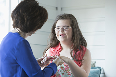 A teenage girl with down syndrome smiling and looking into her grandmother
