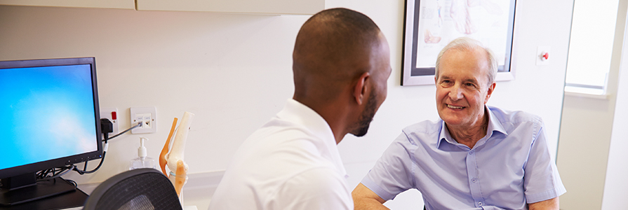 Senior Male Patient Working With Physiotherapist In Hospital