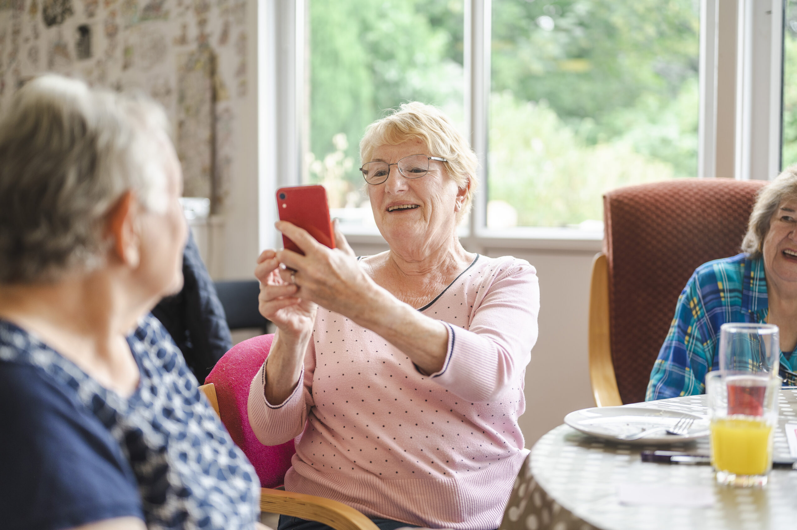 Elderly woman using a red smartphone