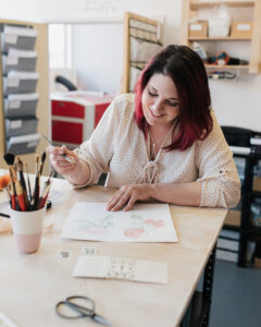 woman, smiling and painting a picture.