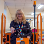 Photo of Karen Weites driving a shuttle buggy through a hospital