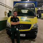 Photo of Paul Purvis standing in front of an ambulance