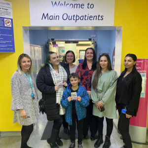Group of women and a child standing outside a sign that says 'Welcome to main outpatients'